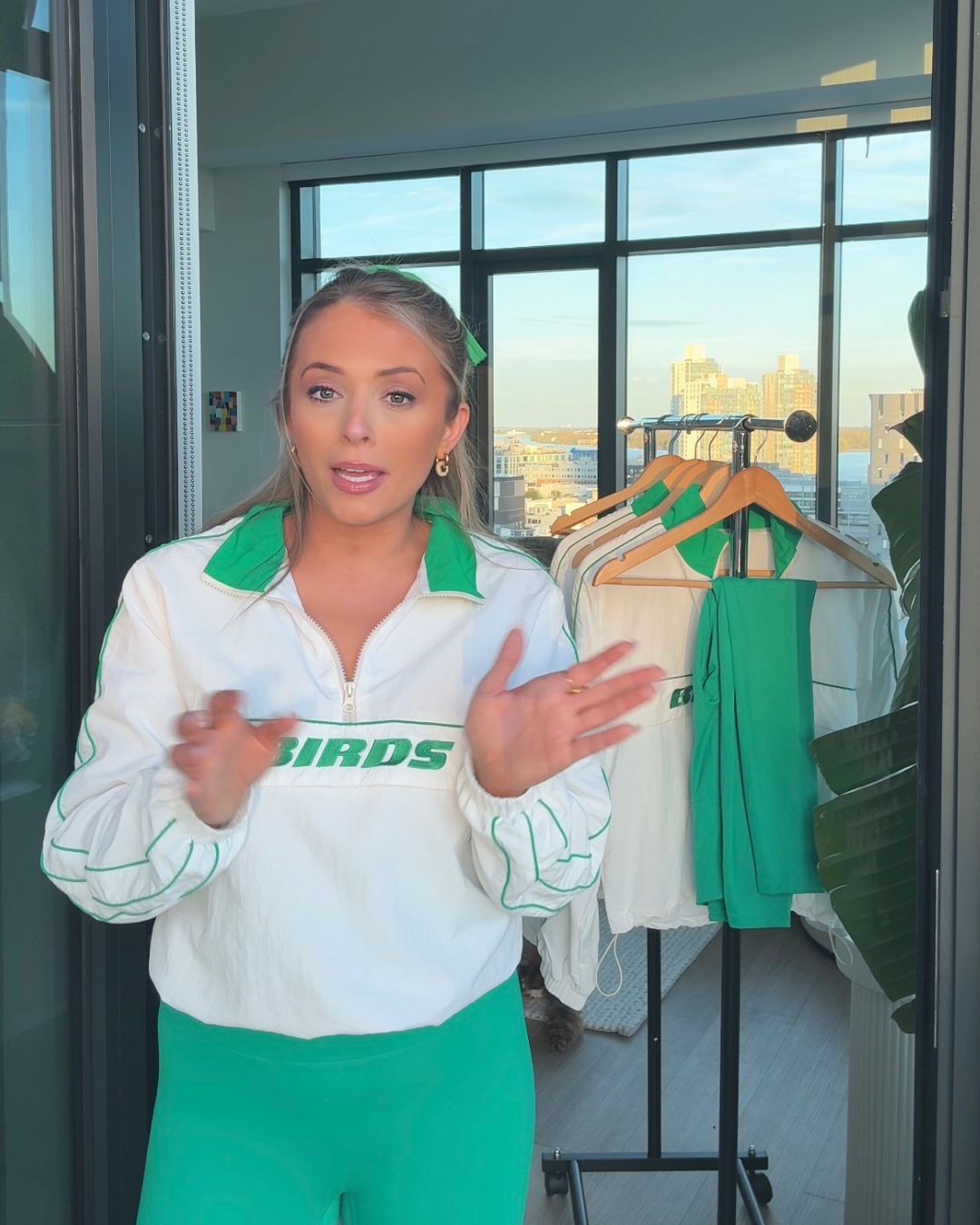 South & Green Co-Founder and Designer, Brooke, wearing the South & Green BIRDS Windbreaker and Kelly Green Yoga Pants  in an apartment with a city view.