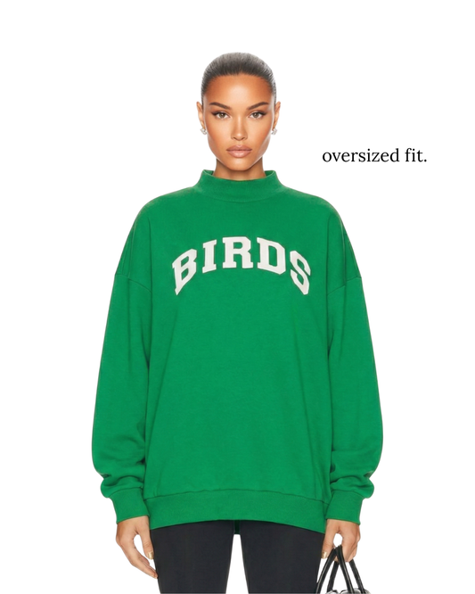Model wearing an oversized fit of South & Green's BIRDS Varsity Mockneck in Kelly Green.  