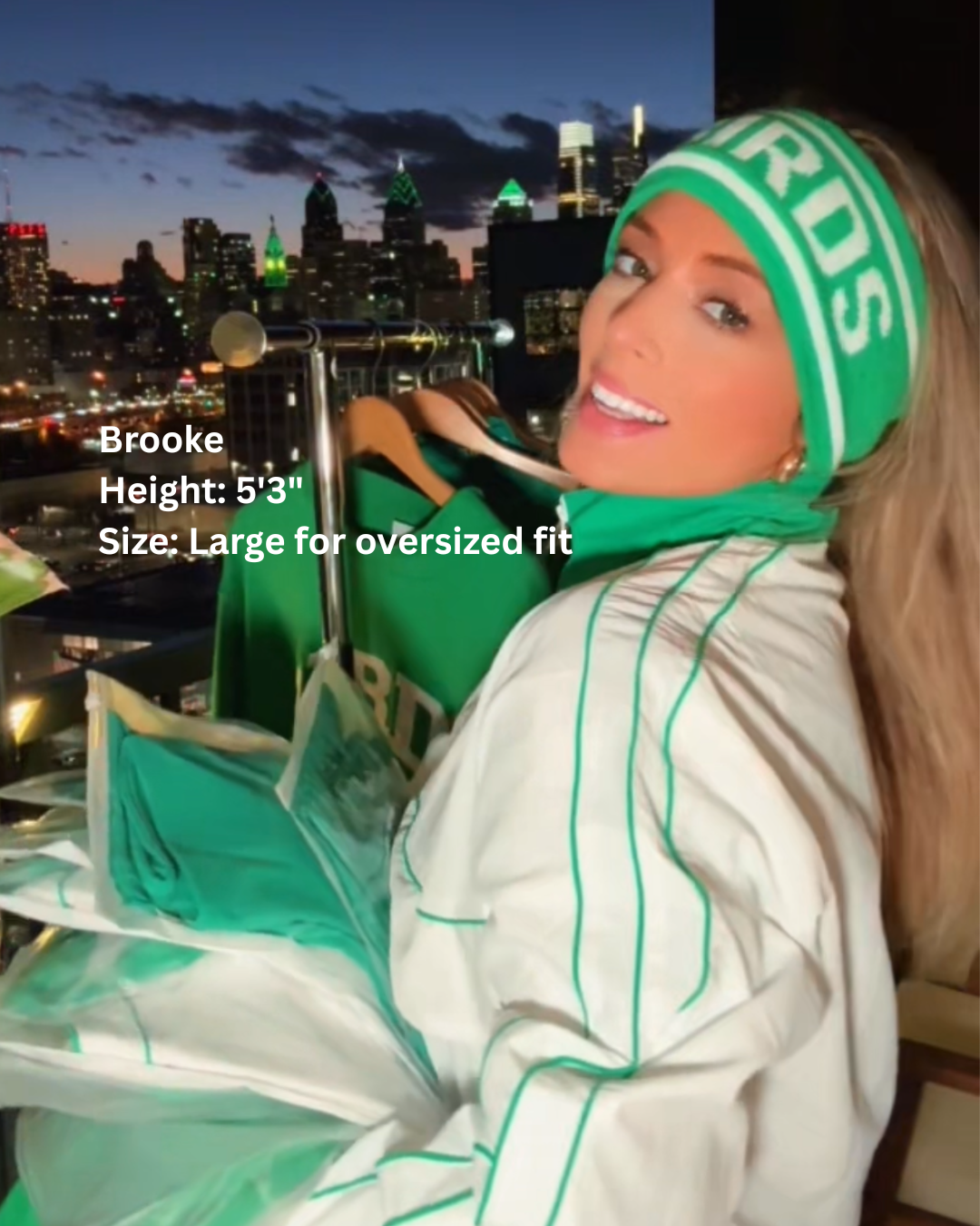 Brooke wearing South & Green's BIRDS Windbreaker and BIRDS Ski Headband, standing outside in front of Philadelphia's cityscape.